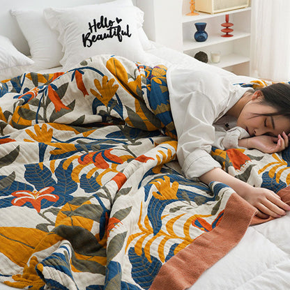 Floral cotton quilt pulled up over a sleeping woman, the terracotta border along its edge