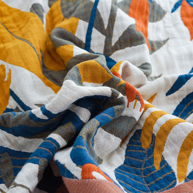 Close-up of the woven cotton gauze, mustard, blue, olive and orange leaves on cream with the terracotta border at one corner