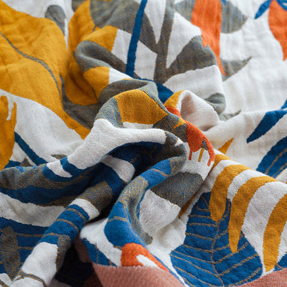 Close-up of the woven cotton gauze, mustard, blue, olive and orange leaves on cream with the terracotta border at one corner