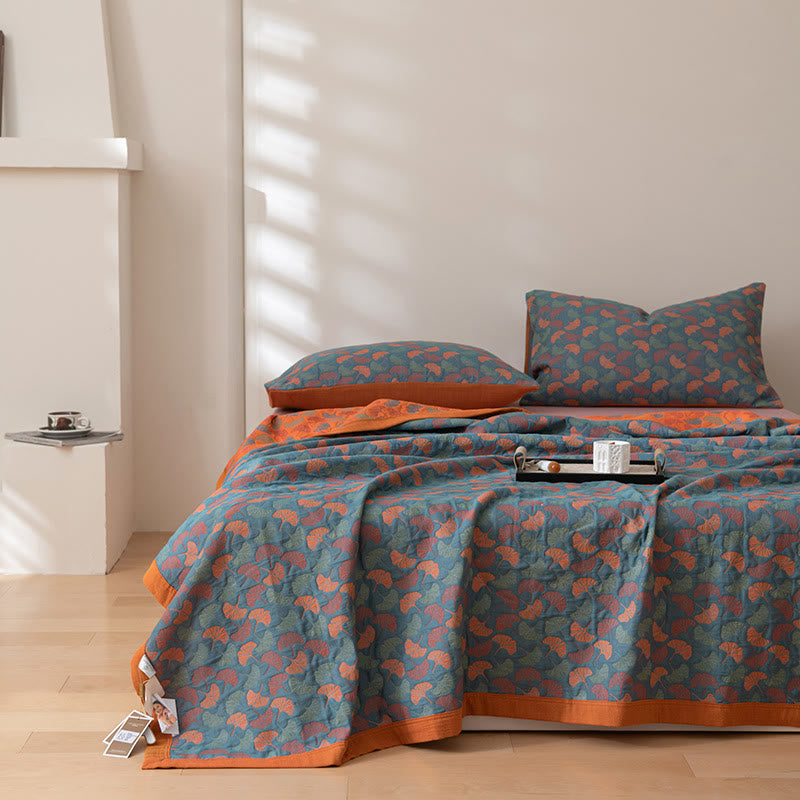 Reversible teal and orange ginkgo quilt over a bed in a bright room, a tray resting on top