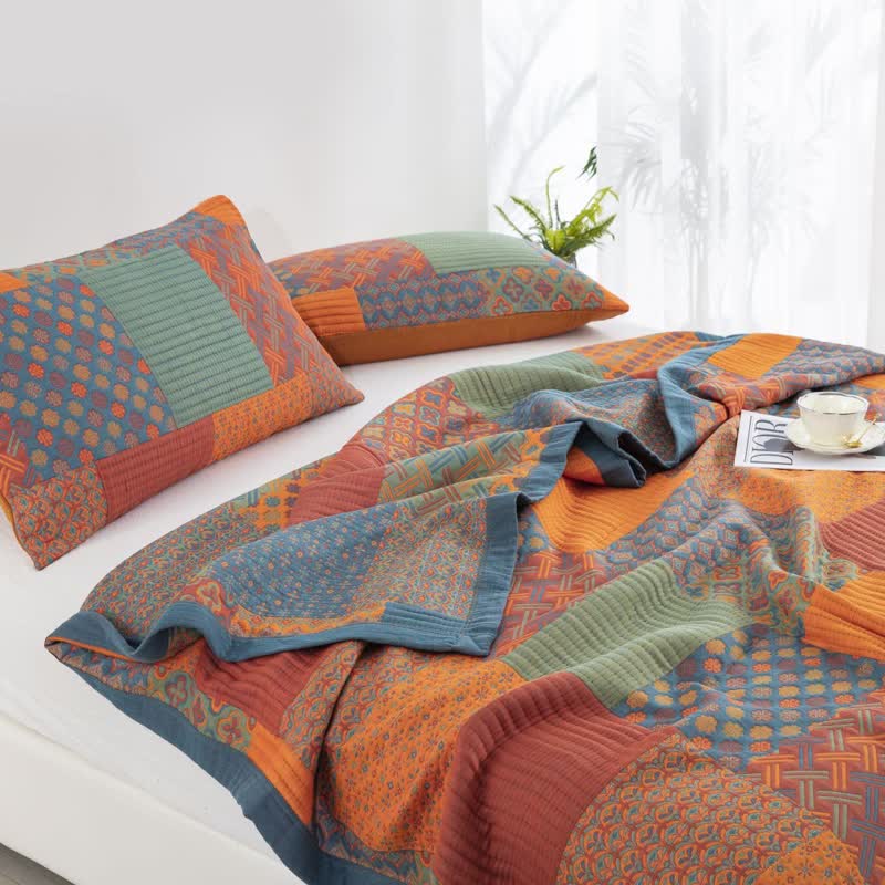 Two patchwork pillowcases on a white bed beside the quilt, one corner turned back to show the blue-led underside and the slate blue border