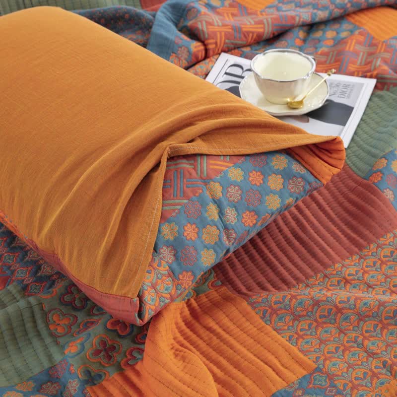 A matching pillowcase lying on the quilt, its plain orange gauze back folded over the patchwork front