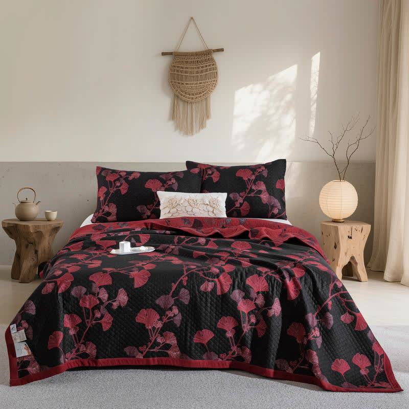 Black ginkgo quilt with red leaves spread over a bed, matching pillowcases, a red reverse at the head and a red border