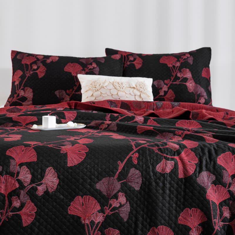 Black ginkgo quilt with red and rose leaves on a bed, matching pillowcases and the red reverse folded back at the head