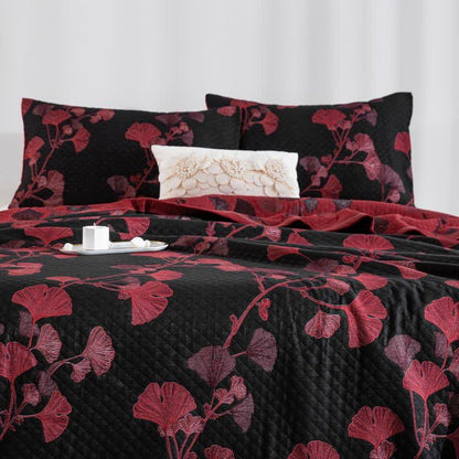 Black ginkgo quilt with red and rose leaves on a bed, matching pillowcases and the red reverse folded back at the head