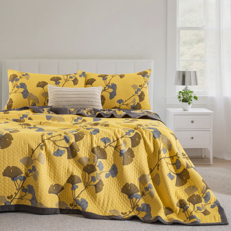 Yellow ginkgo branch quilt on a bed with matching pillowcases, brown and slate blue leaves and a charcoal border