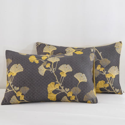 Two charcoal gray quilted pillowcases with yellow ginkgo branches and a thin yellow piped edge