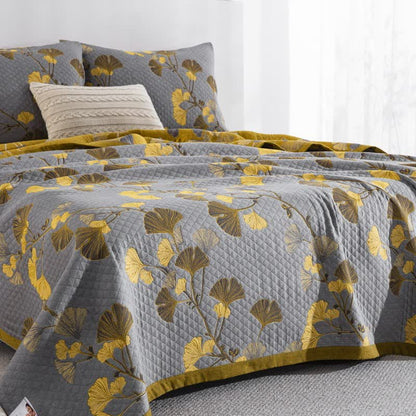 Close view of the gray ginkgo quilt on a bed, diamond quilting with yellow and brown leaves and the mustard border