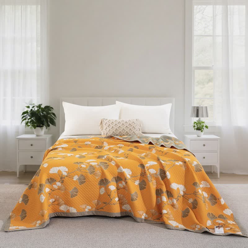Orange ginkgo quilt on a bed with plain white pillows, white and taupe leaves and the sage gray reverse at the head