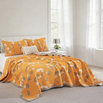 Orange ginkgo quilt on a bed by a bright window, matching pillowcases and the sage gray border at the corner