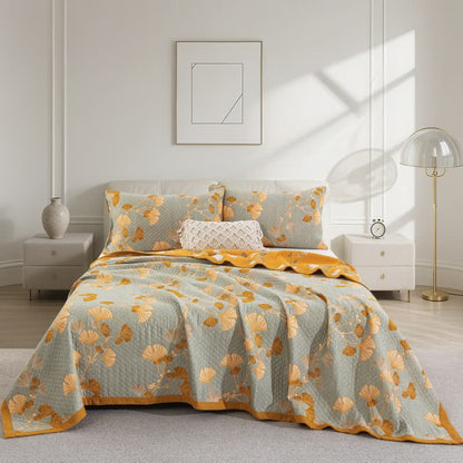 Pale sage gray ginkgo quilt with orange and cream leaves on a bed, matching pillowcases and an orange border