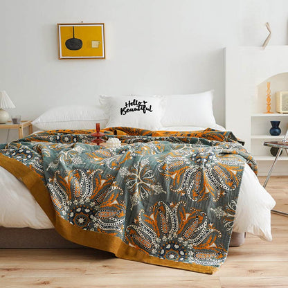 Dark teal floral cotton quilt spread over a bed, orange and white paisley medallions with a wide mustard border and the orange reverse at the head