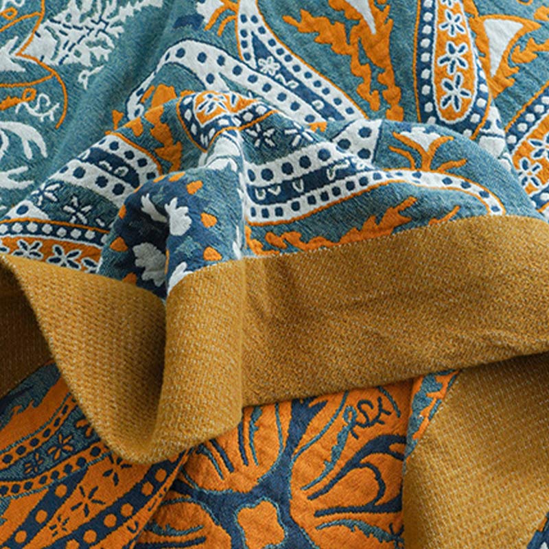 Close-up of the quilt edge folded over, the woven mustard border between the teal front and the orange and navy reverse
