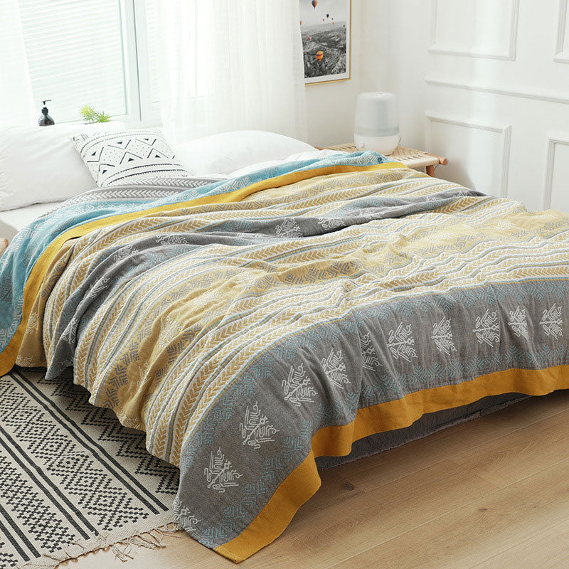 Wheat ear cotton quilt spread over a bed, mustard and white chevron stripes with gray and gold bands and a wide mustard border