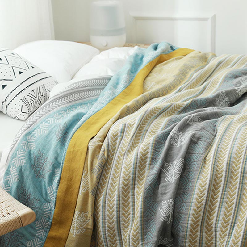 Cotton gauze quilt on a bed with the aqua blue reverse folded back at the pillows and the mustard border between the two sides