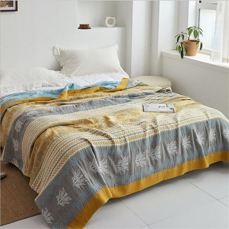 Striped cotton quilt covering a bed by a bright window, a strip of the aqua reverse showing at the head