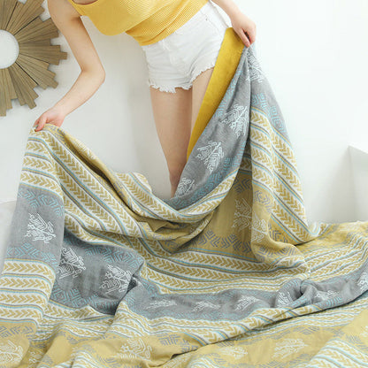 Cotton quilt held open by two corners, showing the wheat ear stripes, gray bands and mustard border across its width