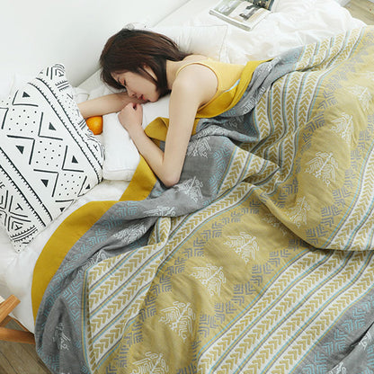 Striped cotton quilt pulled over a sleeping woman, seen from above, the mustard border along the edge