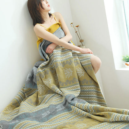 Woman seated by a window wrapped in the wheat ear cotton quilt, the stripes falling to the floor