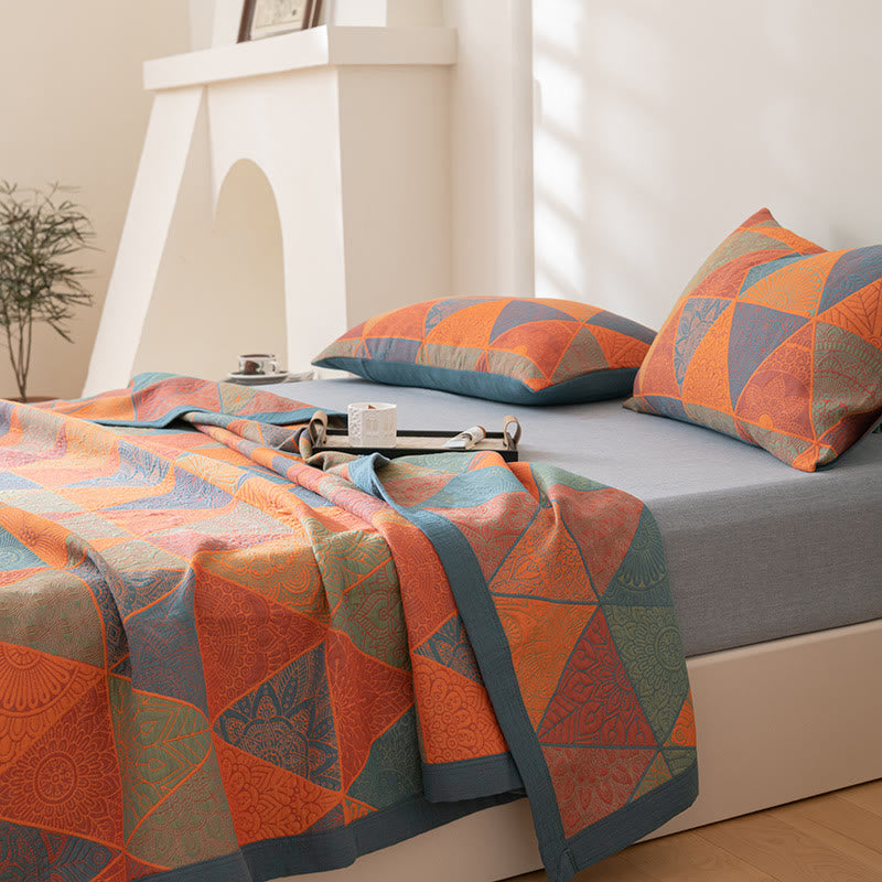 Reversible muslin quilt half pulled back on a bed, showing the triangle pattern and slate blue border