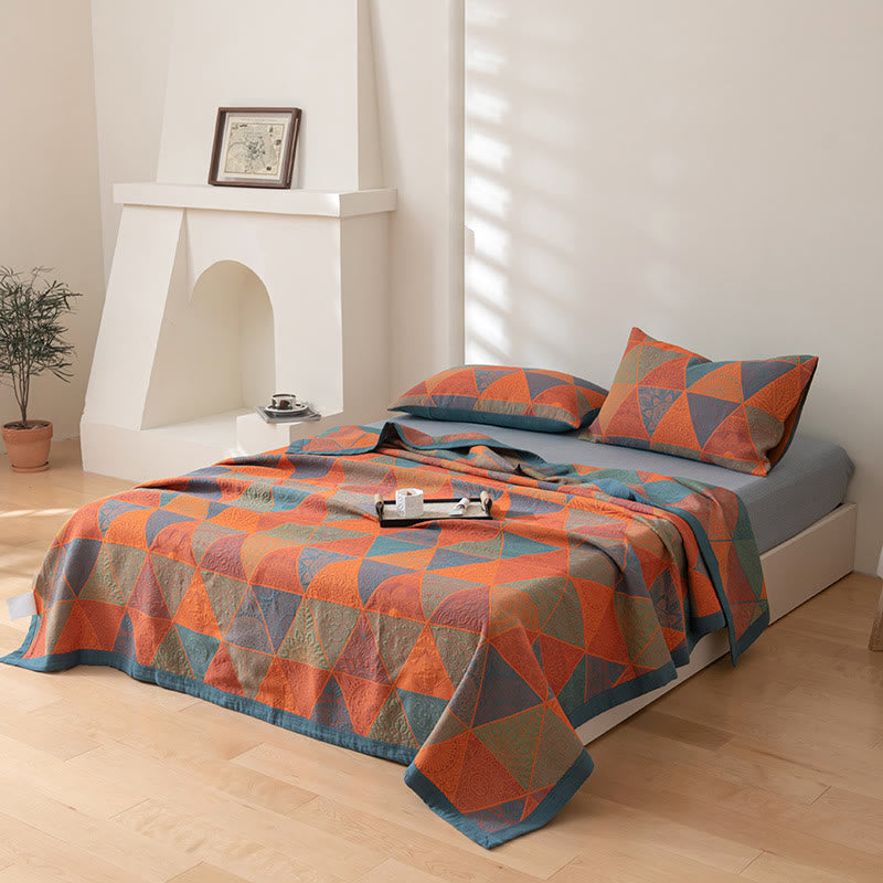 Orange triangle quilt and two matching pillowcases on a made bed