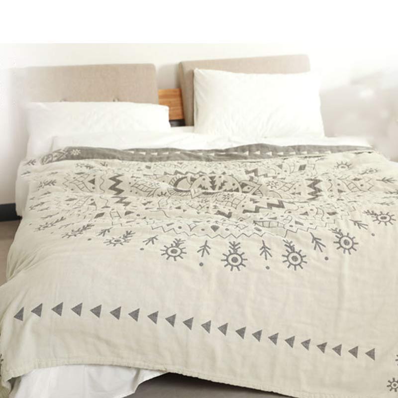 Gray mandala quilt over a bed with the dark gray reverse folded back below the pillows