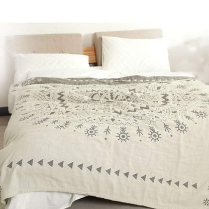 Gray mandala quilt over a bed with the dark gray reverse folded back below the pillows