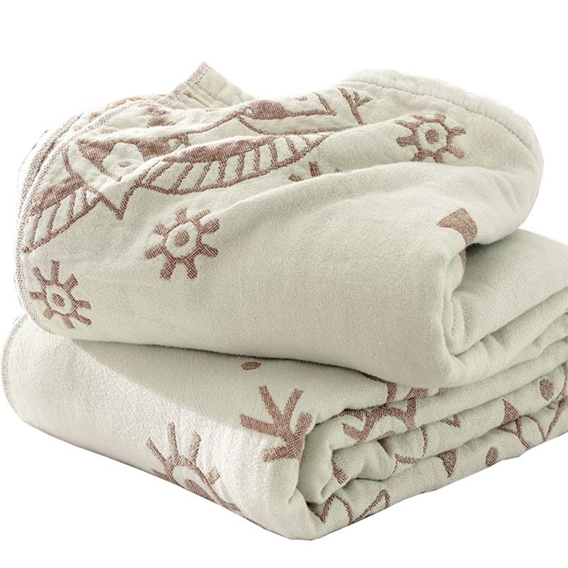 Brown mandala cotton quilt folded on a white background, rose-brown sun motifs on cream