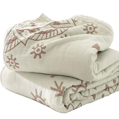 Brown mandala cotton quilt folded on a white background, rose-brown sun motifs on cream