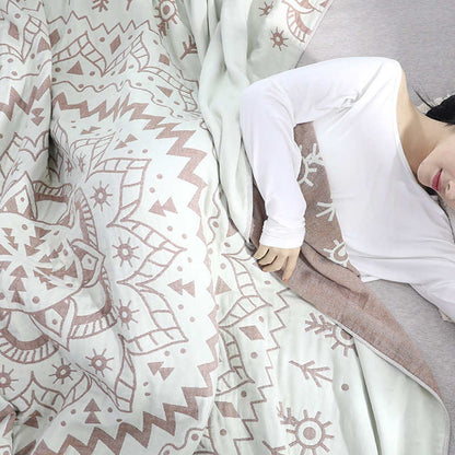 Woman lying under the brown mandala quilt, the rose-brown reverse folded back beside her arm