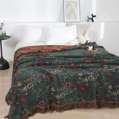 Dark green floral cotton blanket spread over a bed, burgundy and cream flowers on pale vines, the rust reverse folded back at the pillows