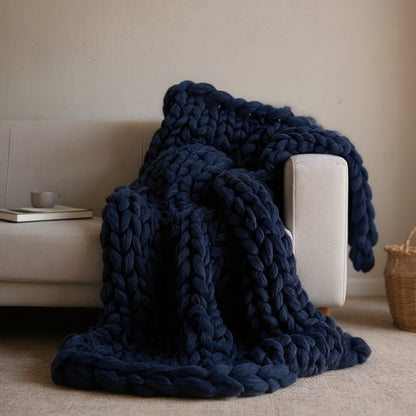 Navy chunky knit throw draped over the arm of a cream sofa and pooling on the rug
