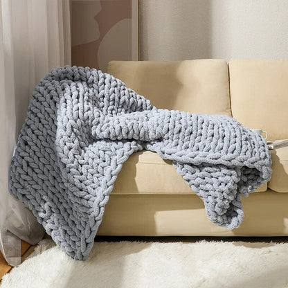 Silver chunky chenille knit throw draped over a cream sofa and falling onto a white rug, its big loops catching the light