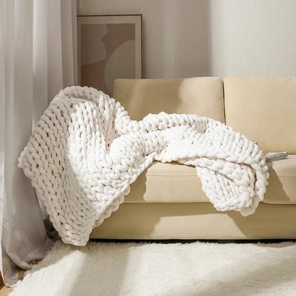 White chunky chenille knit throw draped over the seat and back of a cream sofa in soft daylight