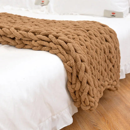 Camel tan chunky chenille throw draped over the end of a white bed above a wood floor