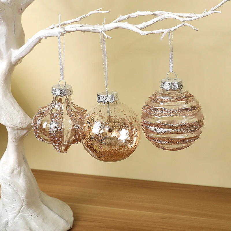 Three rose gold baubles hanging from a white branch: droplet, copper sequin and swirl designs