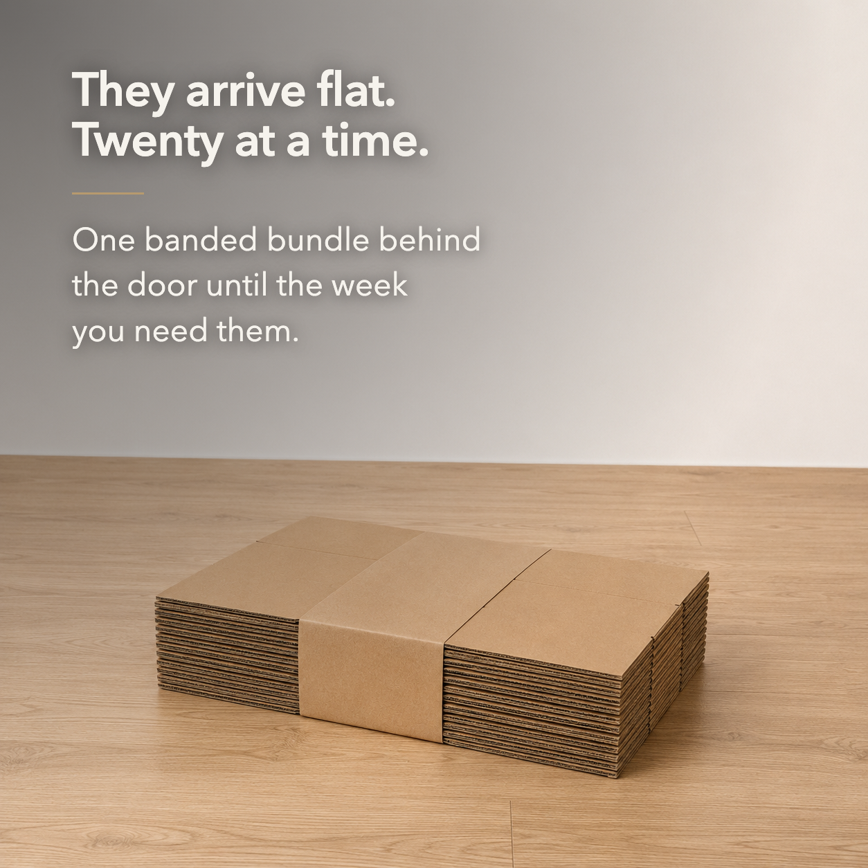 They arrive flat, twenty at a time - a banded flat bundle of cardboard moving boxes on a wood floor