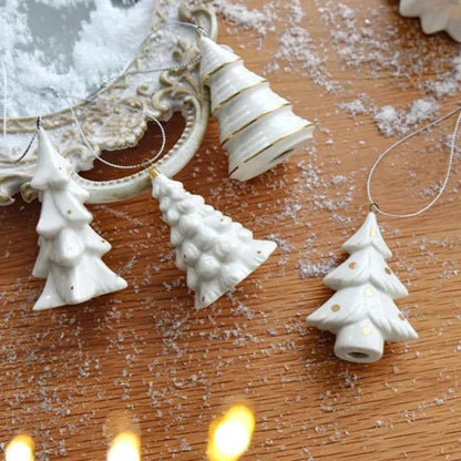 Spruce, Frosted, Cone and Polka Dot ceramic ornaments with silver cords lying on a wooden table with artificial snow