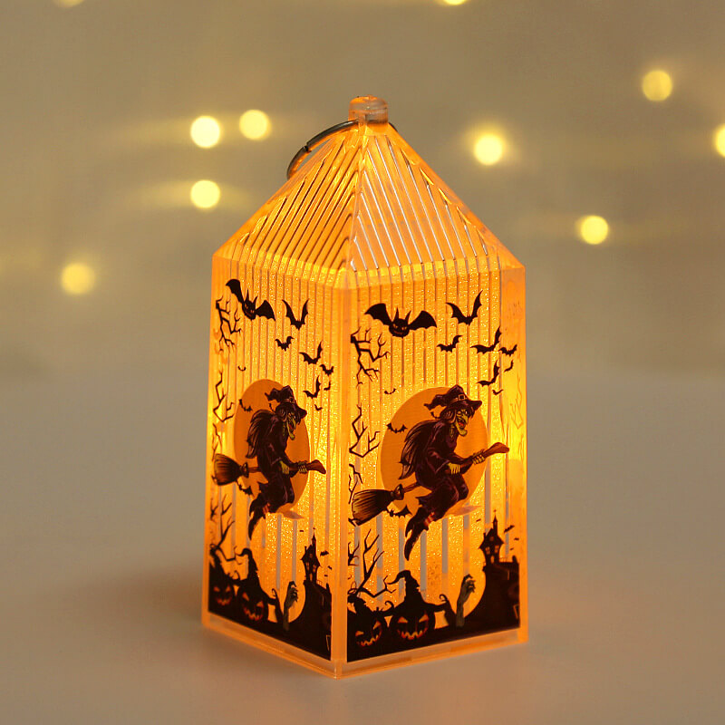 Mini Halloween lantern lit warm amber, printed with a witch on a broomstick flying across a full moon
