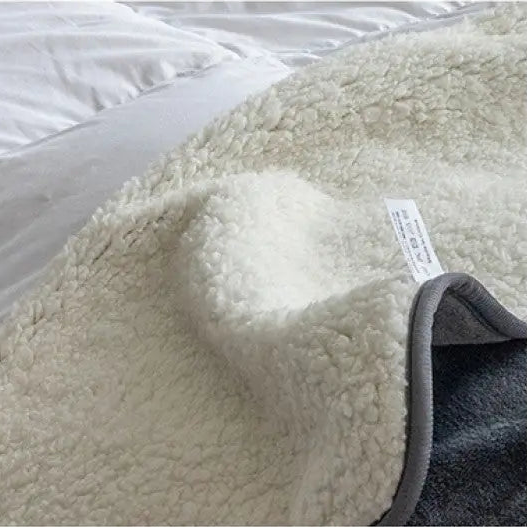 Close-up of the thick, curly off-white fleece side with the gray binding at one corner