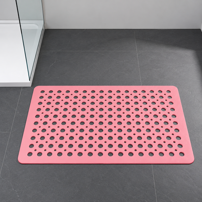 Pink non slip shower mat with drainage holes on a dark slate bathroom floor