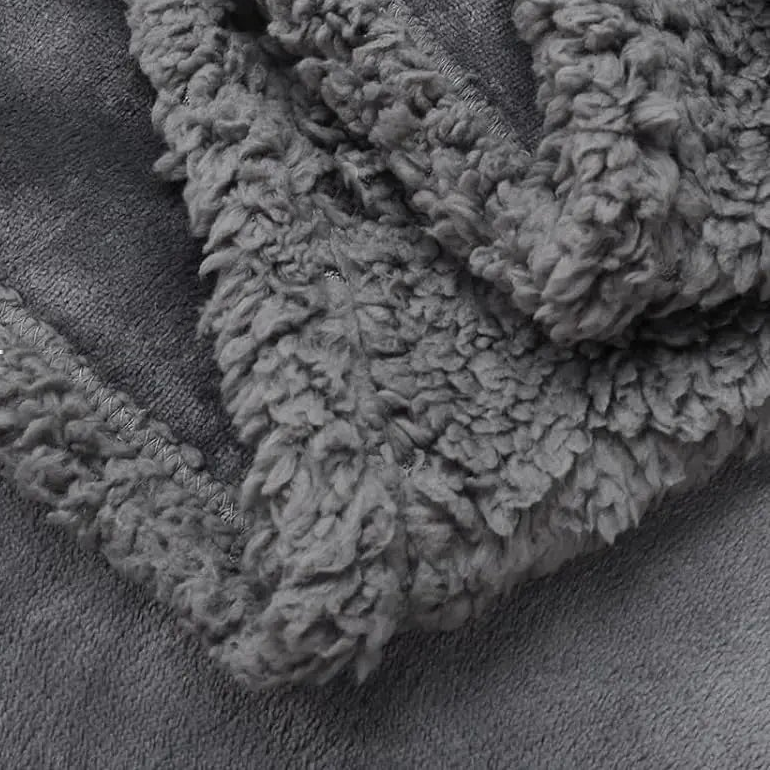 Close-up of the gray curly sherpa side folded over the smooth plush face, with the stitched binding at the edge