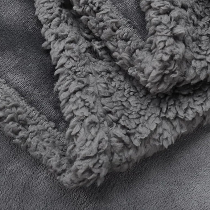 Close-up of the gray curly sherpa side folded over the smooth plush face, with the stitched binding at the edge