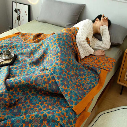 Someone asleep under the reversible quilt, the orange side folded back at the pillow