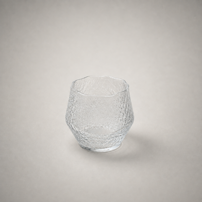 Hammered whiskey tumbler with a wavy uneven rim, shown empty on a plain grey background