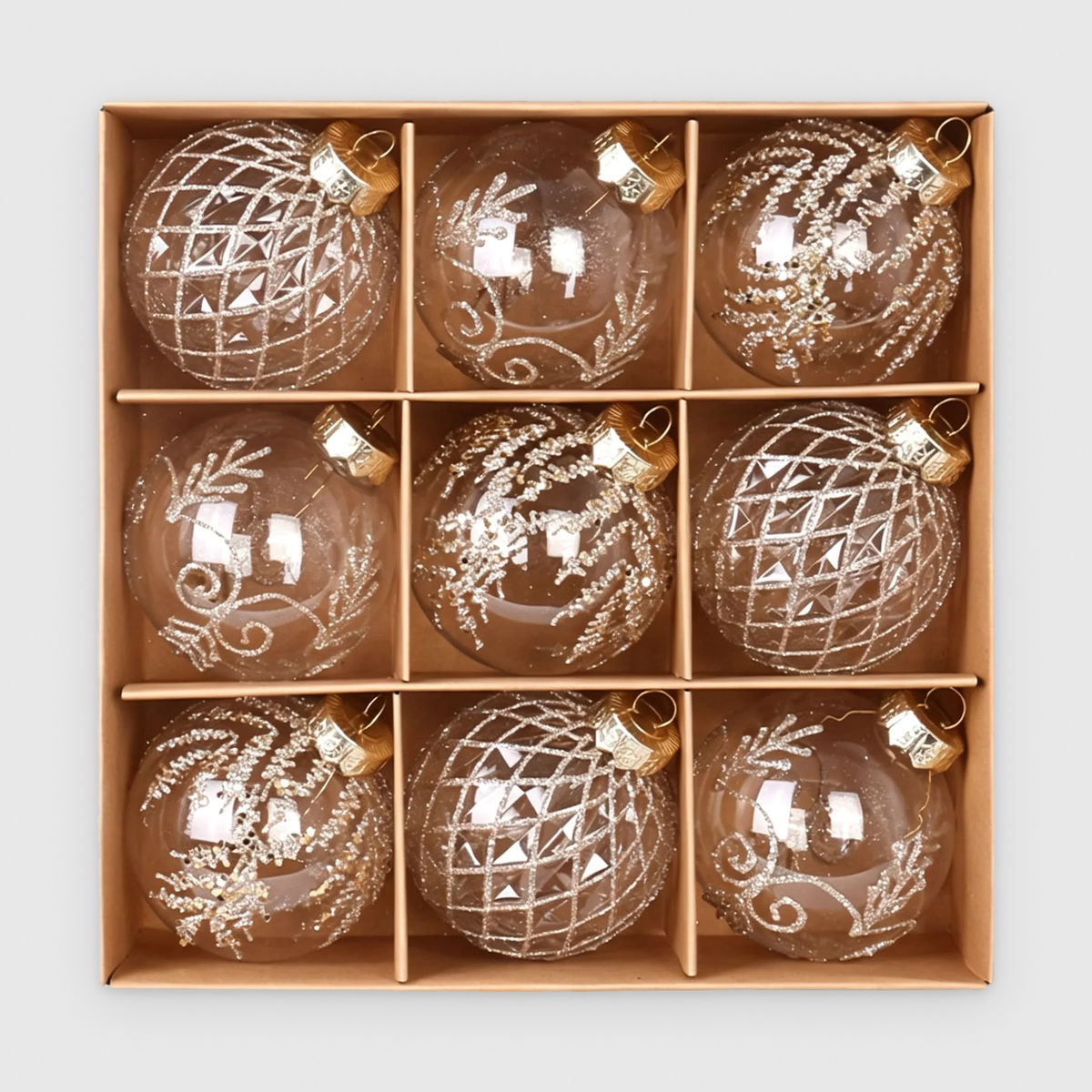 Box of 9 clear Christmas baubles with champagne glitter lattice, scroll and frond designs and gold caps