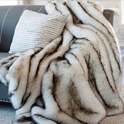 Silver faux fur throw heaped on a gray sofa beside a cushion, the black-tipped ridges running across it