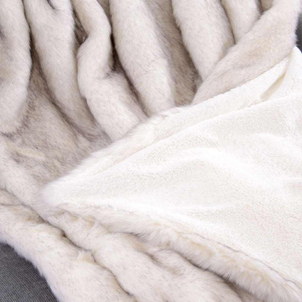 Corner of the white throw turned over to show the smooth cream velvet back under the fur