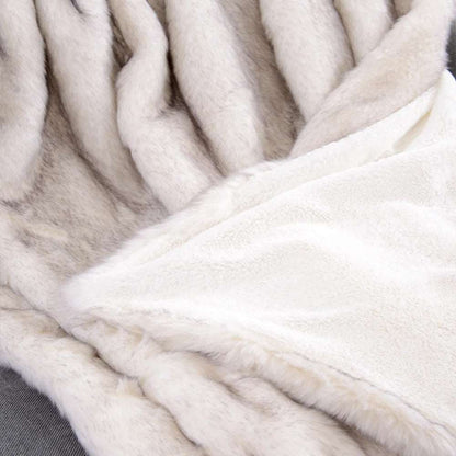 Corner of the white throw turned over to show the smooth cream velvet back under the fur