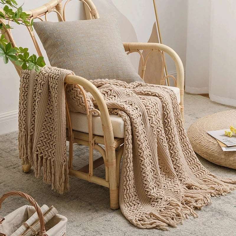 Beige crochet knit throw over a rattan armchair, one end hanging over the arm and the tassel fringe resting on a pale rug
